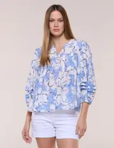 Blusa holgada de gasa estampada con diseño floral en tonos celestes y blancos, escote en V y mangas tres cuartos abullonadas con alforzas horizontales.