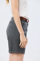 Bermuda clásica de corte recto, confeccionada en algodón con elastano, con bolsillos laterales y vuelta en el ruedo. Incluye un cinturón delgado de cuero marrón.