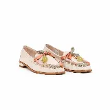 Mocasín de cuero color off-white vainilla, con taco bajo, punta redondeada y detalles artesanales de tiras entrelazadas en tonos pastel y aplique colgante con cuenta translúcida en el empeine.