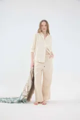 Camisa oversize de lino color beige, de calce relajado, con cuello clásico y cierre frontal de botones. Cuenta con detalles de puntillas en la parte delantera.