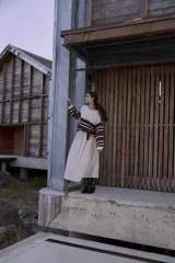 Falda larga plisada color beige, de silueta amplia y caída fluida, con cintura elástica y lazo decorativo color bordó.