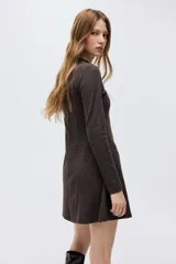Vestido mini de manga larga confeccionado en punto fino suave, con cuello redondo. Presenta costuras decorativas en el frente y falda con vuelo.