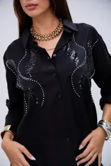 Camisa negra de manga larga con detalles de lentejuelas y bordados en el pecho, cuello camisero y cierre de botones.