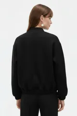Campera estilo bomber color negro, de manga larga, con cierre frontal y bolsillos.