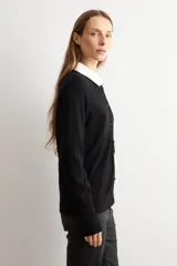Cardigan de punto fino color negro, con cuello redondo, cierre frontal de botones y mangas largas.
