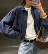 Chaqueta tipo bomber de gamuza azul marino, con cuello camisero, cierre frontal y mangas amplias, de corte a la cintura.