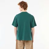 Remera verde oscuro de manga corta y corte holgado, con cuello redondo y delicado bordado frontal en contraste.