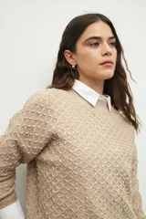 Sweater de punto con textura en relieve, cuello redondo y mangas largas con puños ajustados.