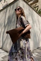 Vestido midi de manga corta, con diseño holgado, cuello redondo y estampado abstracto con detalles florales en tonos marrones y violetas.