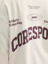 Buzo de manga larga color blanco roto (sea salt) con cuello redondo y calce oversize cropped. Presenta un estampado gráfico en la espalda con texto en color borgoña, incluyendo las palabras "RESPORT", "ATHLETIC ESSENTIALS", "CREATIVE DEPT." y el año "1990".