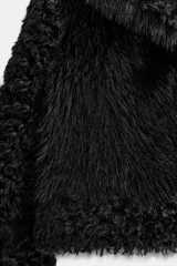 Abrigo corto de Zara Woman Collection con cuello de solapa y manga larga. Presenta una combinación de texturas con aplicación de pelo sintético y diseño de efecto rizado en mangas y bordes. Cuenta con forro interior y cierre frontal mediante ganchos metálicos.