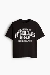 Remera negra de algodón con cuello redondo, manga corta y hombros caídos, de corte holgado. Presenta un estampado gráfico frontal estilo universitario en color blanco con efecto desgastado que lee "PROPERTY OF PHYS. ED. CLASS 1905 STATEN ISLAND".