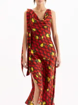 Vestido largo al tobillo confeccionado en seda de color rojo con estampado de limones y peras. Posee escote buche, diseño sin mangas, tajos laterales y detalle de tiras colgantes en el hombro.