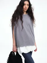 Top de silueta amplia y corte recto, confeccionado en tejido de punto liviano color gris con sutiles destellos de micro lentejuelas. Presenta cuello redondo y mangas cortas caídas.