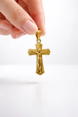 Dije de cruz con figura de Cristo en relieve, acabado en tono dorado brillante.