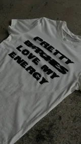 Remera blanca de manga corta, corte al cuerpo, con estampa frontal en negro con la leyenda "Pretty Bitches Love My Energy".