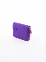 Billetera pequeña de diseño compacto en color violeta, con cierre perimetral y logo circular grabado en el frente.