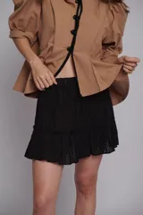 Falda corta negra de broderie de algodón con cintura elástica y volados en el ruedo.