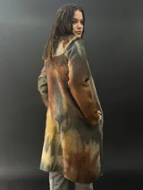 Tapado largo gris de lana merino con bolsillos laterales y corte particular en los hombros.