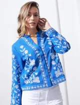 Chaqueta de algodón bordada, color azul con bordado floral blanco, con cuello a la base y escote en V, abertura central con botón.