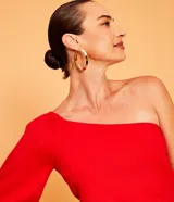 Blusa roja de lino con un solo hombro y manga larga abullonada.