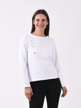 Remera Mahalo de manga larga en color blanco, con cuello redondo y detalle de botones dorados dispuestos en diagonal desde el hombro derecho hasta el pecho.
