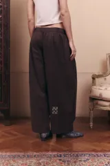 Pantalón de gabardina impermeable color marrón chocolate, con silueta amplia y relajada. Presenta cintura elastizada con pinzas delanteras que aportan volumen y movimiento a la prenda.