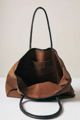 Bolso tipo tote de gamuza color marrón con detalles de bordes y asas en cuero negro.