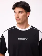 Remera de corte holgado en color negro con detalles en blanco en el cuello y paneles laterales. Presenta logo de la marca estampado en el centro del pecho.