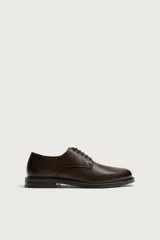 Zapato de vestir tipo derby, color marrón oscuro, con parte superior lisa, horma redonda, cordones y suela con ligero tacón.