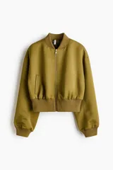 Campera bomber de tejido grueso color verde militar, con cuello corto acanalado, cierre frontal y bolsillos insertados. Cuenta con hombros caídos, mangas abullonadas y puños y bajo acanalados.