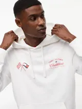 Buzo con capucha de Tommy Hilfiger en colaboración con Cadillac Formula 1 Team. Confeccionado en algodón, presenta un diseño de corte regular con hombros caídos, bolsillo tipo canguro y puños acanalados. En el pecho incluye un gráfico bordado con banderas cruzadas y el logo de la colaboración.
