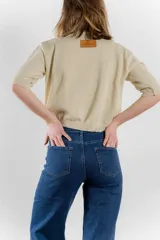 Sweater de punto color tostado con hilos metalizados, de corte recto, escote redondo y mangas cortas con puño ajustado.