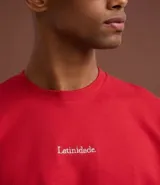 Remera masculina roja de corte recto, cuello redondo y mangas cortas. Presenta un lettering centralizado con la palabra "latinidade" en blanco.