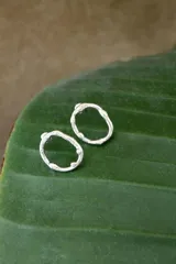 Par de aros de alpaca con forma circular irregular.