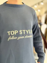 Sweater de punto color beige con cuello redondo, manga larga y diseño estampado en el pecho con las frases "TOP STYLE" y "follow your dreams" en color marrón.