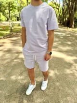 Conjunto deportivo compuesto por una remera de manga corta y un short lila con cordón de ajuste blanco.
