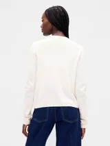 Saco de punto fino color marfil, con cuello redondo, cierre frontal con botones y mangas largas.