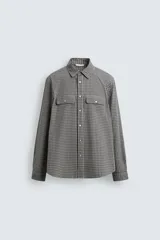 Camisa de corte regular fit confeccionada en tejido de algodón con estampado de cuadros. Presenta cuello solapa, manga larga con puños abotonados, cierre frontal de botones y dos bolsillos de plastrón con solapa en el pecho.