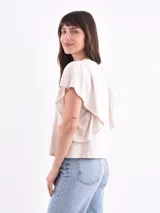Remera blanca de algodón con cuello redondo y mangas cortas con volados fruncidos en los hombros.