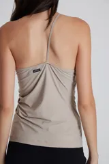 Top asimétrico negro, ajustado al cuerpo, con un solo bretel fino que cruza sobre un hombro. Presenta frunces laterales.