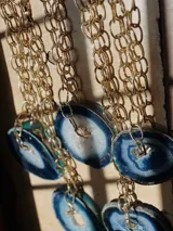 Collar con cadena de eslabones gruesos dorados y dije de rodaja de ágata natural teñida de azul y blanco.
