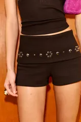 Shorts de algodón color marrón oscuro, con cintura elástica de tiro medio y detalle de rib con tachas metálicas decorativas.