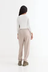 Pantalón jogger de felpa color marrón, con cintura elástica ajustable mediante cordón, bolsillos laterales y puños elásticos en los tobillos.