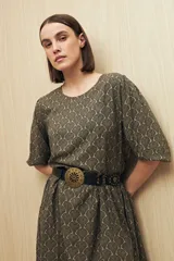 Vestido corto con estampado animal print en tonos beige, negro y marrón. Tiene corte holgado, mangas cortas y falda con vuelo.