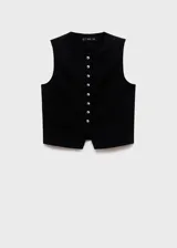 Chaleco de sastrería negro con cuello redondo, sin mangas, diseño recto y bolsillos de ribete laterales. Cuenta con cierre frontal de botones con efecto joya.