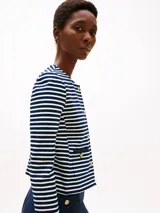 Campera corta de punto con diseño a rayas horizontales azules y blancas, cuello redondo y cierre frontal con botones dorados decorativos.