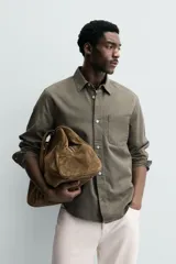 Camisa de corte relajado confeccionada en una mezcla de lyocell y algodón con efecto lavado. Presenta cuello solapa, manga larga con puños abotonados, bolsillo de plastrón en el pecho y cierre frontal con botones.