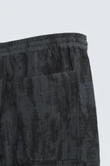 Bermuda de corte relajado, color gris oscuro con efecto tie-dye o textura irregular. Presenta cintura elástica ajustable con cordón y bolsillos laterales y traseros de plastrón.