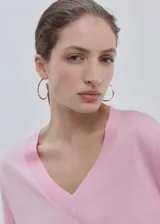 Chaleco de punto fino color rosado, con diseño recto, cuello en V y mangas largas.